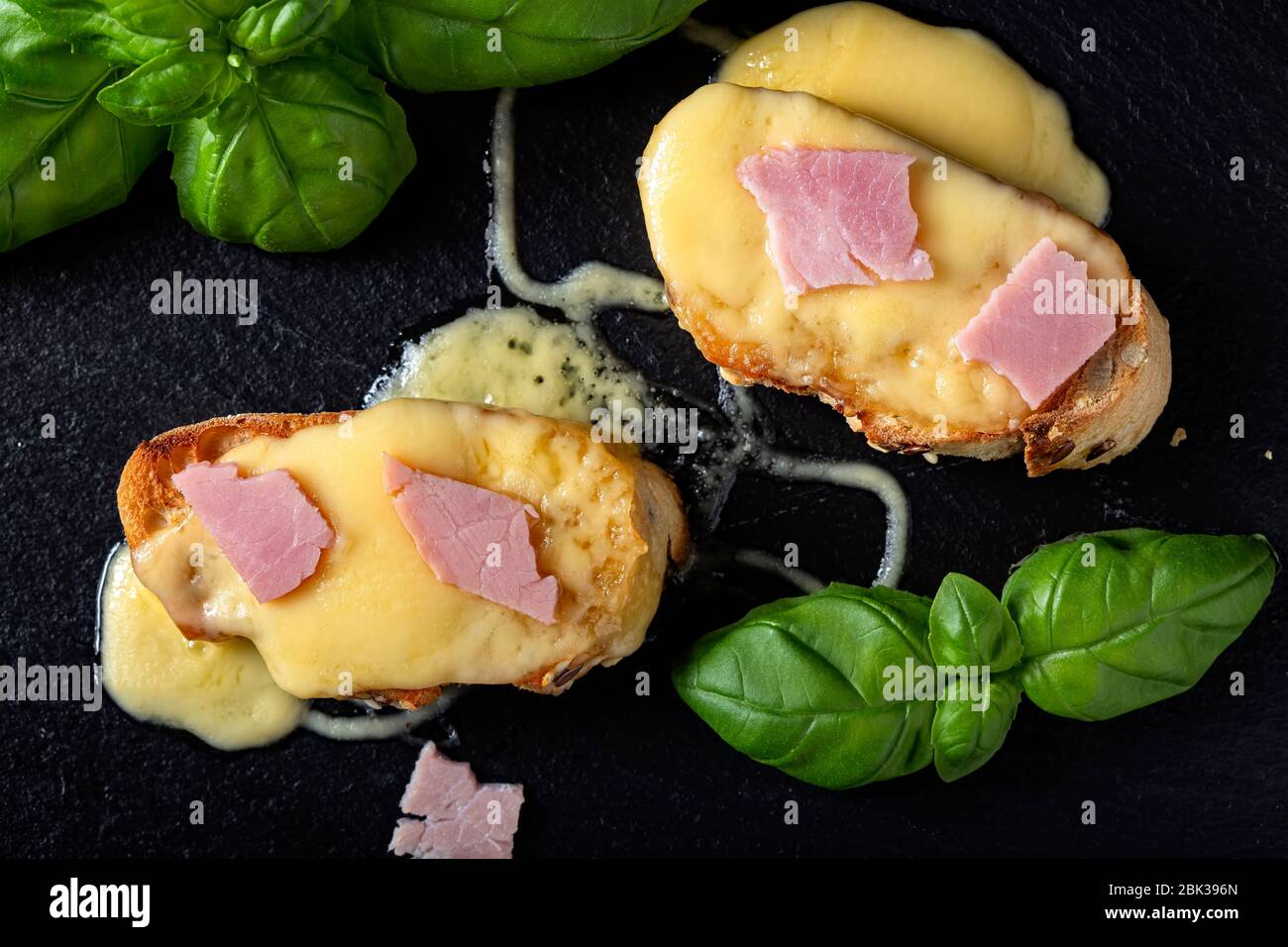 Warm bruschetta with ham, melted cheese and basil - top view Stock Photo