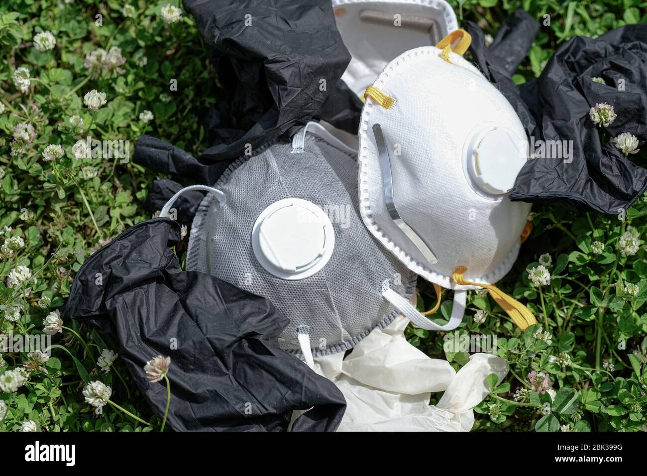Ffp2 protective mask and gloves refuse trash on grass meadow ground.covid coronavirus disease garbage pollution Stock Photo