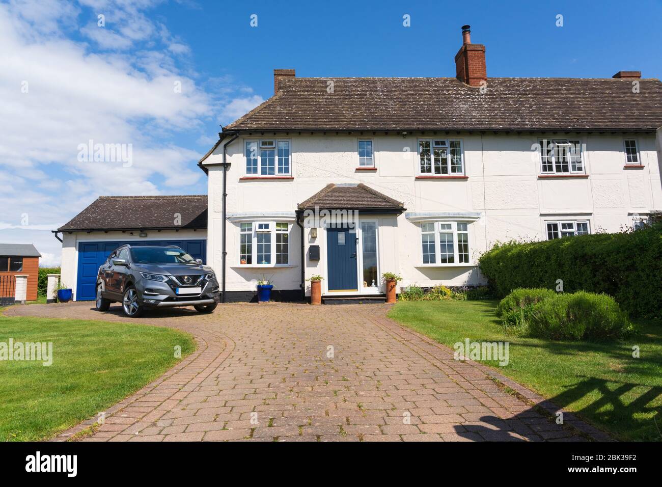 Exterior of a former 1920's semi-detached council house with added porch, double garage and driveway. Version without car in driveway also available. Stock Photo