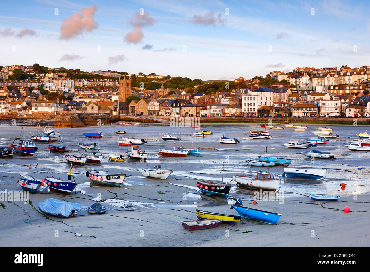 Low tide at St Ives Harbour as the early morning sunlight casts a warm glow over the waterfront Stock Photo