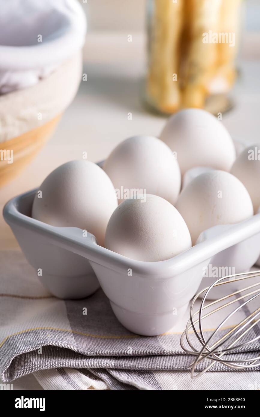Farm freshly picked organic chicken eggs in a ceramic container or tray on a blurred kitchen background, copy space. Healthy natural food concept. Stock Photo