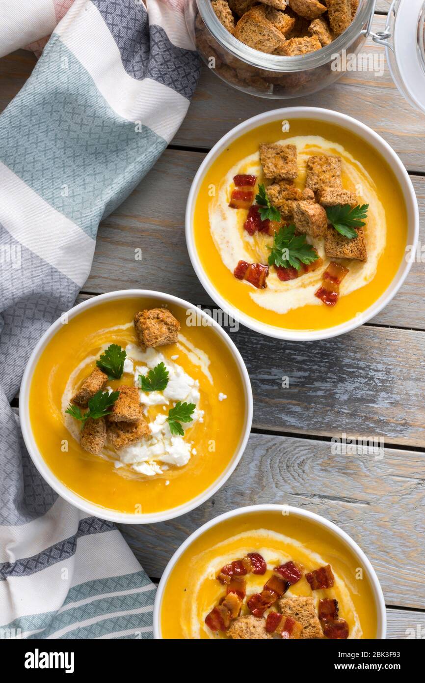 Butternut squash cream soup with milk cream, bacon, croutons, feta cheese and parsley. Top view Stock Photo