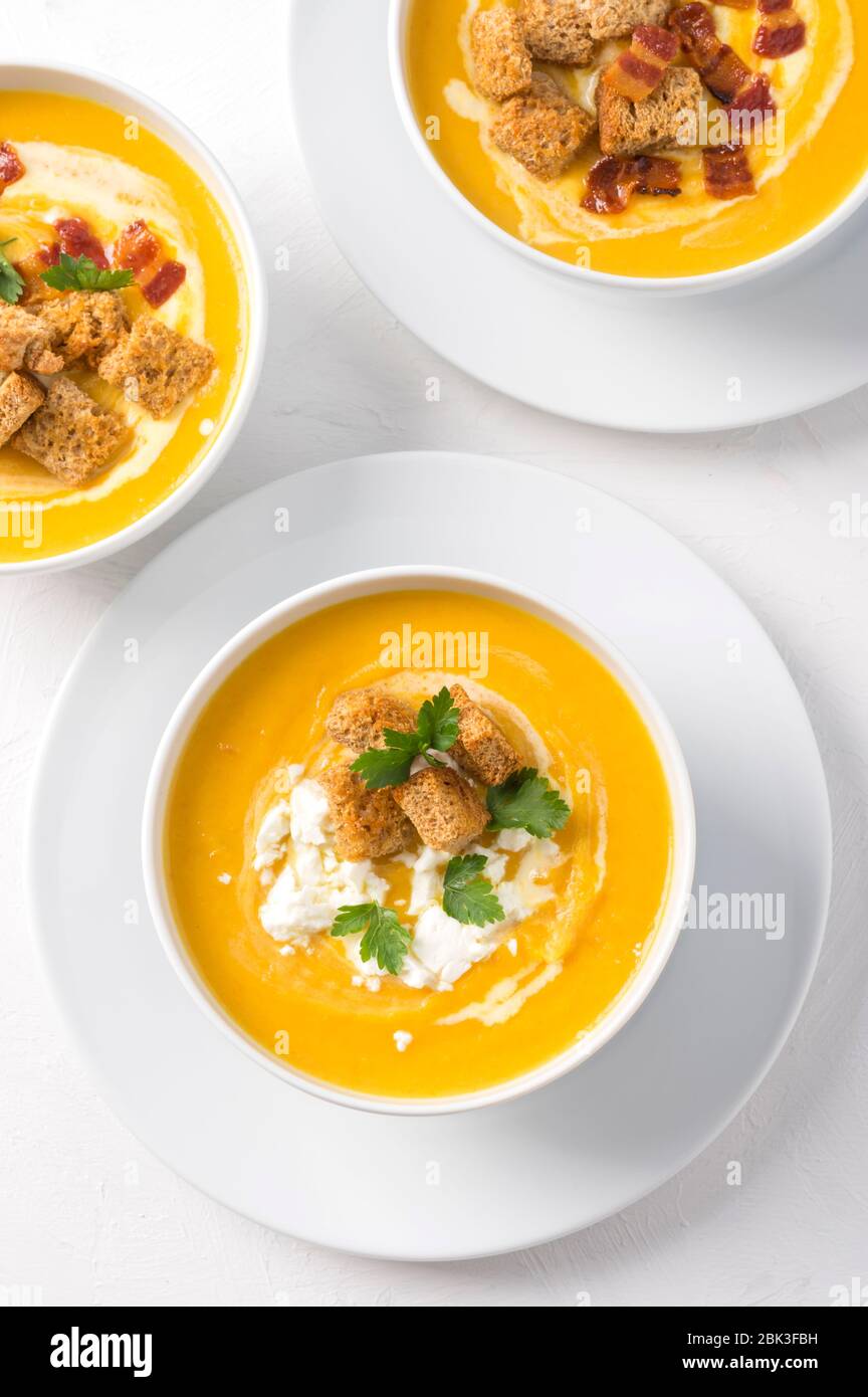 Butternut squash cream soup with milk cream, bacon, croutons, feta cheese and parsley. Top view Stock Photo