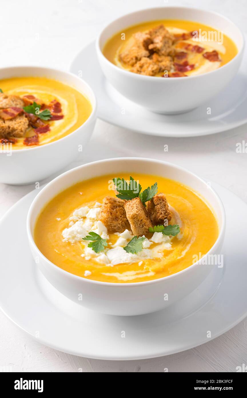 Butternut squash cream soup with milk cream, bacon, croutons, feta cheese and parsley. Front vew Stock Photo