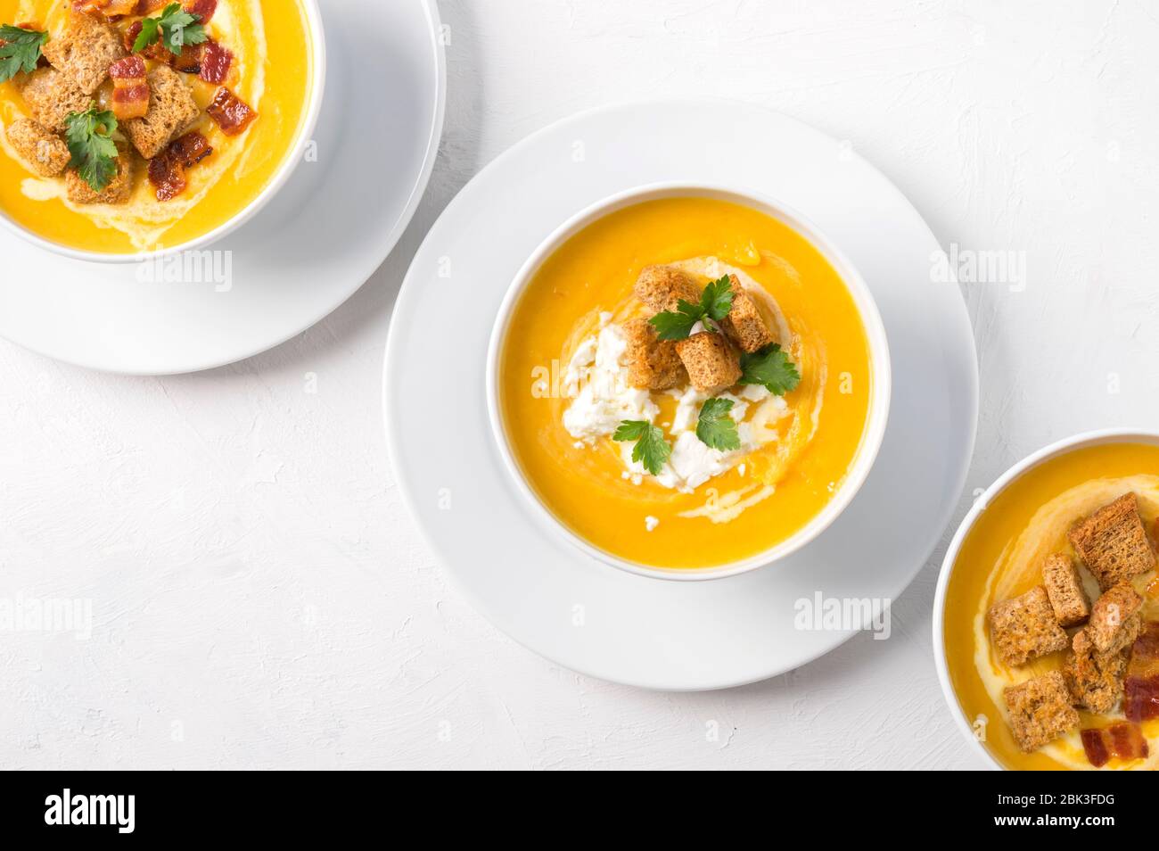 Butternut squash cream soup with milk cream, bacon, croutons, feta cheese and parsley. Top view. Coppy space Stock Photo