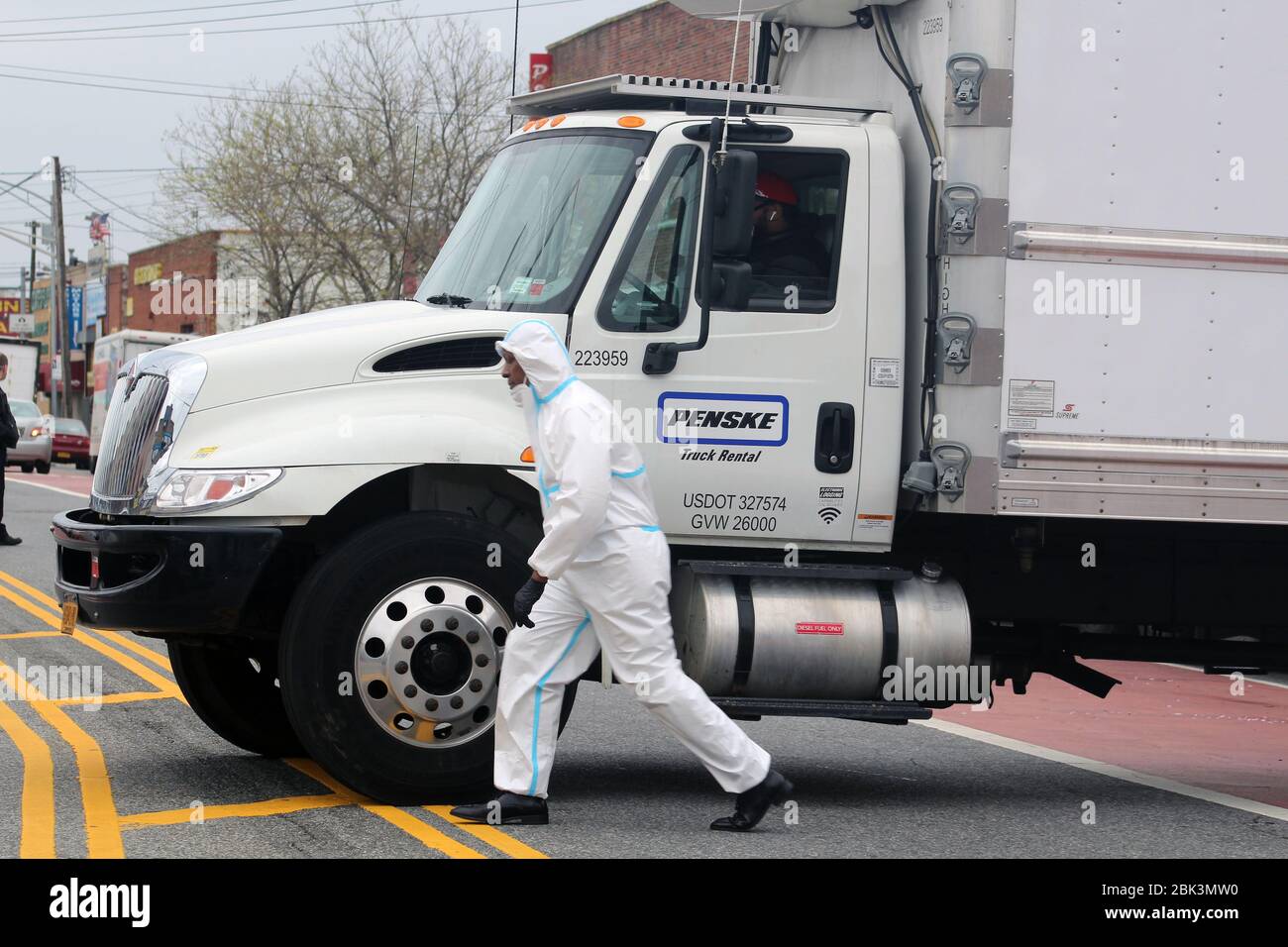 New York, New York, USA. 30th Apr, 2020. A worker dressed in hazmat walks in a hurry in front of a large refrigerated truck next to the Andrew T. Cleckley Funeral Home in Brooklyn where bodies non properly cared have been removed. 60 corpses were stored in 4 rented vehiciles lining the street along stores. Neighbors reported a foul smell and fluids dripping from the trucks. The funeral home was overwhelmed by COVID-19 deaths and ran out of room for bodies, which were awaiting cremation in New York. Credit: Marie Le Ble/ZUMA Wire/Alamy Live News Stock Photo