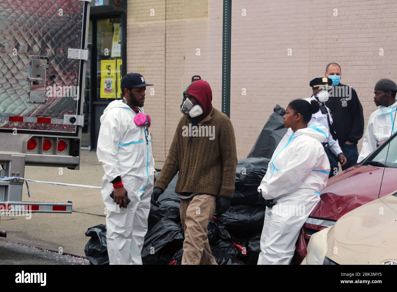 April 30, 2020, New York, New York, USA: Workers dressed in hazmat or masked faces stand in the back of a large refrigerated truck in front of the Andrew T. Cleckley Funeral Home in Brooklyn where bodies that weren't properly cared have been removed. 60 corpses were stored in 4 rented vehiciles lining the street along stores. Neighbors reported a foul smell and fluids dripping from the trucks. The funeral home was overwhelmed by COVID-19 deaths, waiting for weeks for cremations in New York. (Credit Image: © Marie Le Ble/ZUMA Wire) Stock Photo