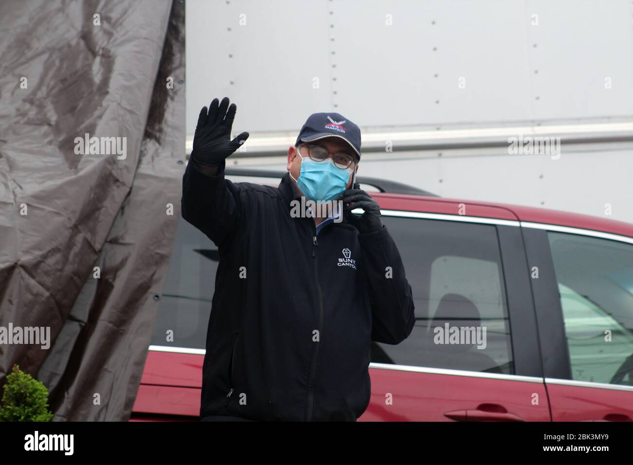 April 30, 2020, New York, New York, USA: This official representing New York City stands on the phone and hand up next to the Andrew T. Cleckley Funeral Home in Brooklyn where bodies non properly cared are removed. 60 corpses were stored in 4 non-refregerated rented trucks lining the street nearby stores. Neighbors reported a foul smell still persistent and fluids dripping from the trucks. Some remains were also found lying on the facilityÃ¢â‚¬â„¢s floor. The funeral home was overwhelmed by COVID-19 deaths. (Credit Image: © Marie Le Ble/ZUMA Wire) Stock Photo