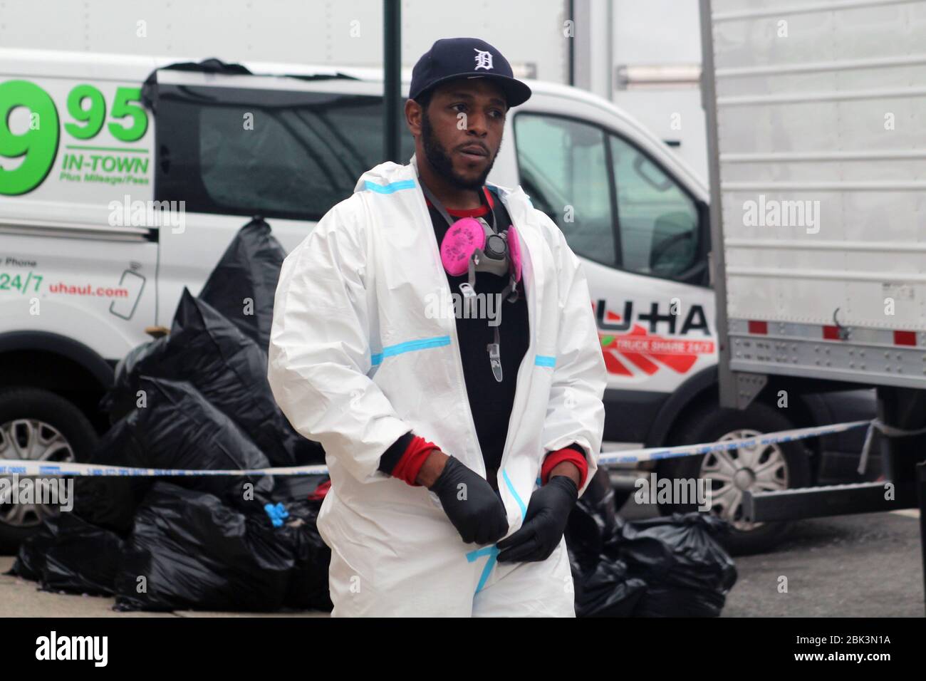 April 30, 2020, New York, New York, USA: This worker, dressed in a hazmat, walks surrounded by trucks. Behind him, big black garbage bags have been piled up in front of the Andrew T. Cleckley Funeral Home in Brooklyn where bodies non properly cared are removed. 60 corpses were stored in 4 non-refregerated rented trucks lining the street nearby stores. Neighbors reported a foul smell still persistent and fluids dripping from the trucks. Some remains were also found lying on the facilityÃ¢â‚¬â„¢s floor. The funeral home was overwhelmed by COVID-19 deaths, waiting for weeks for cremations. (Credi Stock Photo
