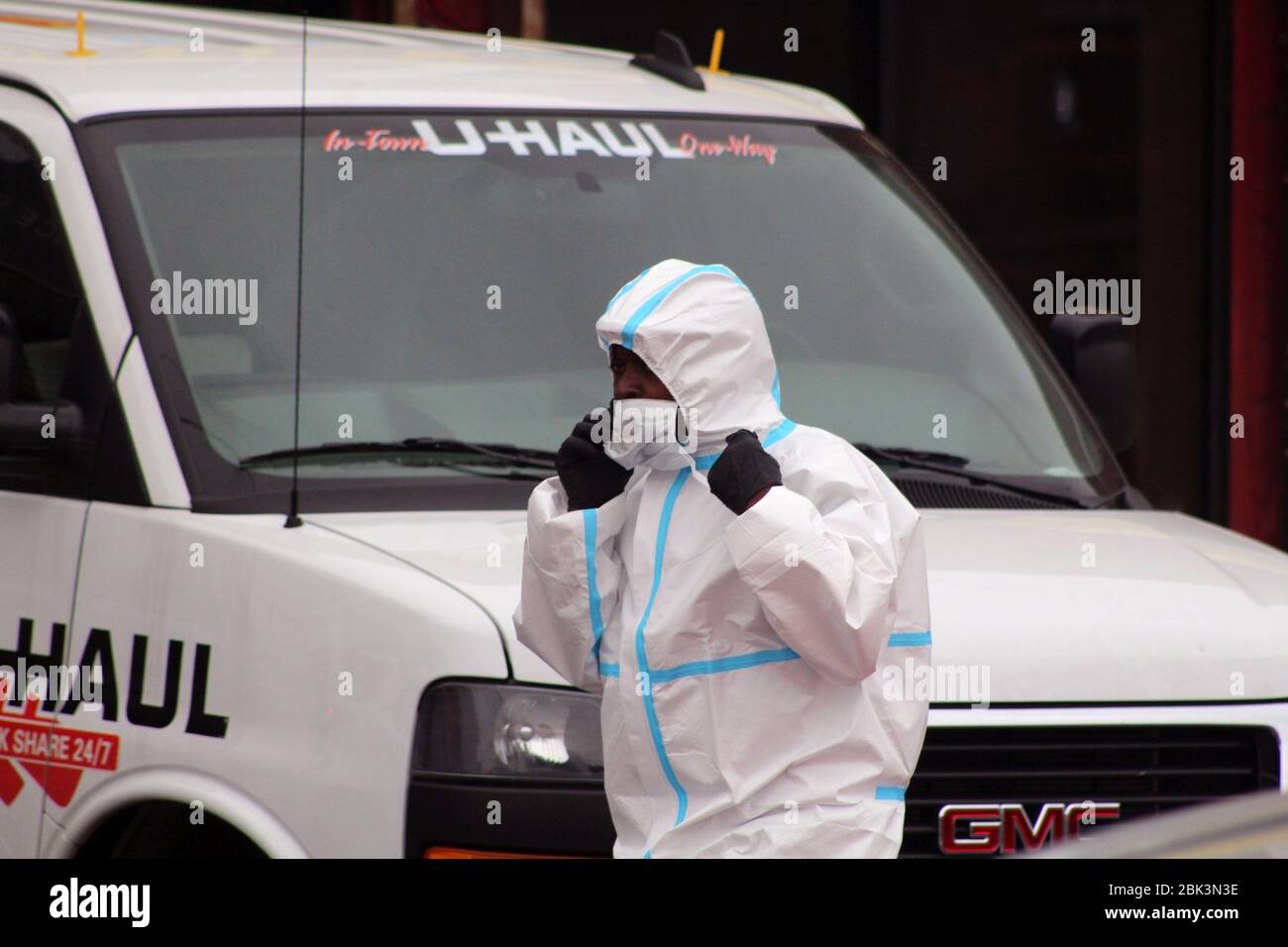 New York, New York, USA. 30th Apr, 2020. This man dressed in a hazmat suit, phone in hand, walks past a U-Haul truck along the Andrew T. Cleckley Funeral Home in Brooklyn where bodies not properly cared are removed. 60 bodies were stored in 4 rented non-refrigerated vehicles including the U-Haul one lining the street along stores. Neighbors reported a foul smell and fluids dripping from the trucks. In New York City alone, there have been almost 13,000 COVID-19 deaths. Credit: Marie Le Ble/ZUMA Wire/Alamy Live News Stock Photo