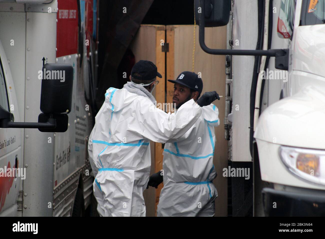 New York, New York, USA. 30th Apr, 2020. This 2 men, dressed in a hazmat, stop between two trucks in front of the Andrew T. Cleckley Funeral Home in Brooklyn where bodies non properly cared are removed. 60 corpses were stored in 4 non-refregerated rented trucks lining the street nearby stores. Neighbors reported a foul smell still persistent and fluids dripping from the trucks. Some remains were also found lying on the facilityÃ¢â‚¬â„¢s floor. The funeral home was overwhelmed by COVID-19 deaths, waiting for weeks for cremations. Credit: Marie Le Ble/ZUMA Wire/Alamy Live News Stock Photo