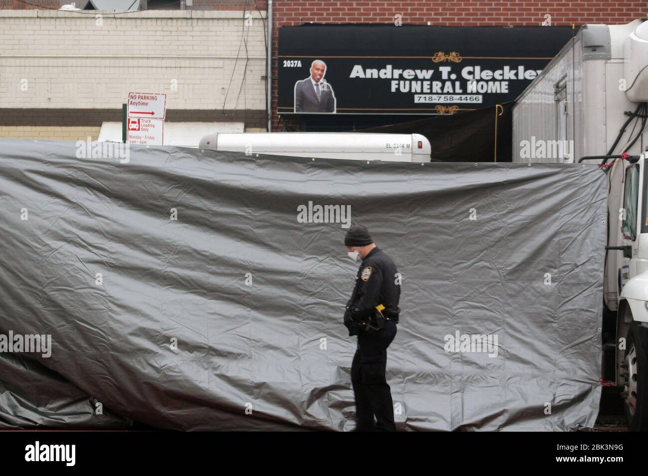 New York, New York, USA. 30th Apr, 2020. A NYPD officer walks past a large brown tarp that has been deployed in front of the Andrew T. Cleckley Funeral Home in Brooklyn where bodies non properly cared are removed. 60 bodies were stored in 4 non-refregerated vehiciles lining the street nearby stores. Neighbors reported a foul smell still persistent and fluids dripping from the trucks. Some remains were also found lying on the facilityÃ¢â‚¬â„¢s floor. The funeral home was overwhelmed by COVID-19 deaths in New York. Credit: Marie Le Ble/ZUMA Wire/Alamy Live News Stock Photo