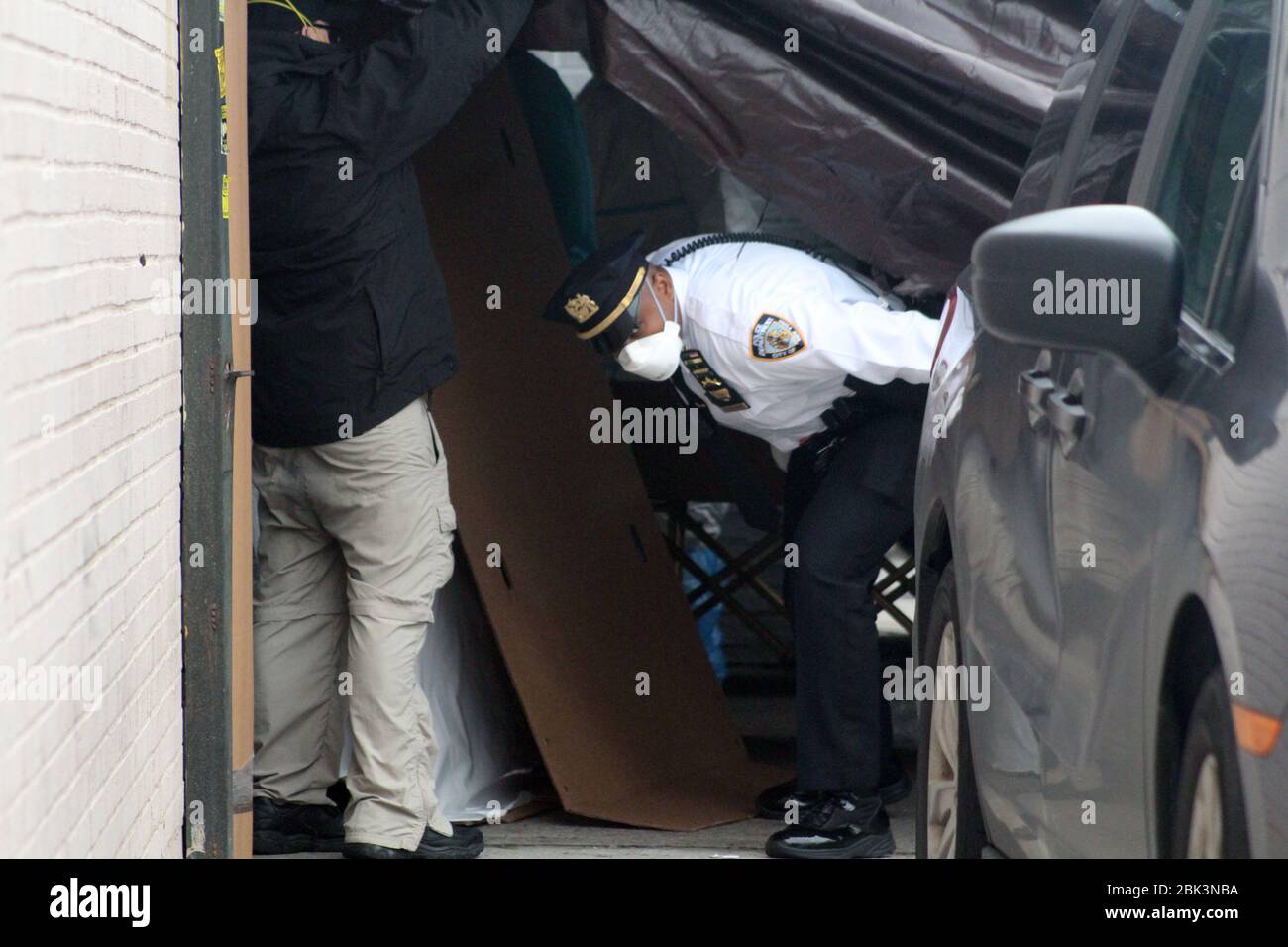 New York, New York, USA. 30th Apr, 2020. A stretcher and cardboard caskets behind him, a NYPD officer passes under the tarpaulin that has been deployed in front of the Andrew T. Cleckley Funeral Home in Brooklyn where bodies non properly cared are removed. 60 bodies were stored in 4 non-refregerated vehiciles lining the street nearby stores. Neighbors reported a foul smell still persistent and fluids dripping from the trucks The funeral home was overwhelmed by COVID-19 deaths in New York. Credit: Marie Le Ble/ZUMA Wire/Alamy Live News Stock Photo