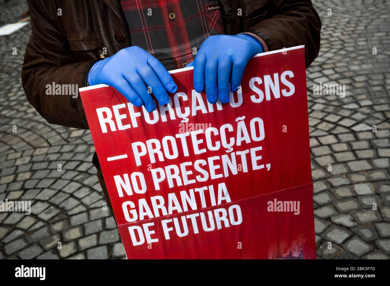 A man stages a silent protest while practicing social distancing to mark Labor Day in Porto, Portugal. Workers were forced to scale back the rallies around the world on May 1, 2020, because of coronavirus lockdowns, although some pushed on with online events and others hit the streets in face masks. Stock Photo