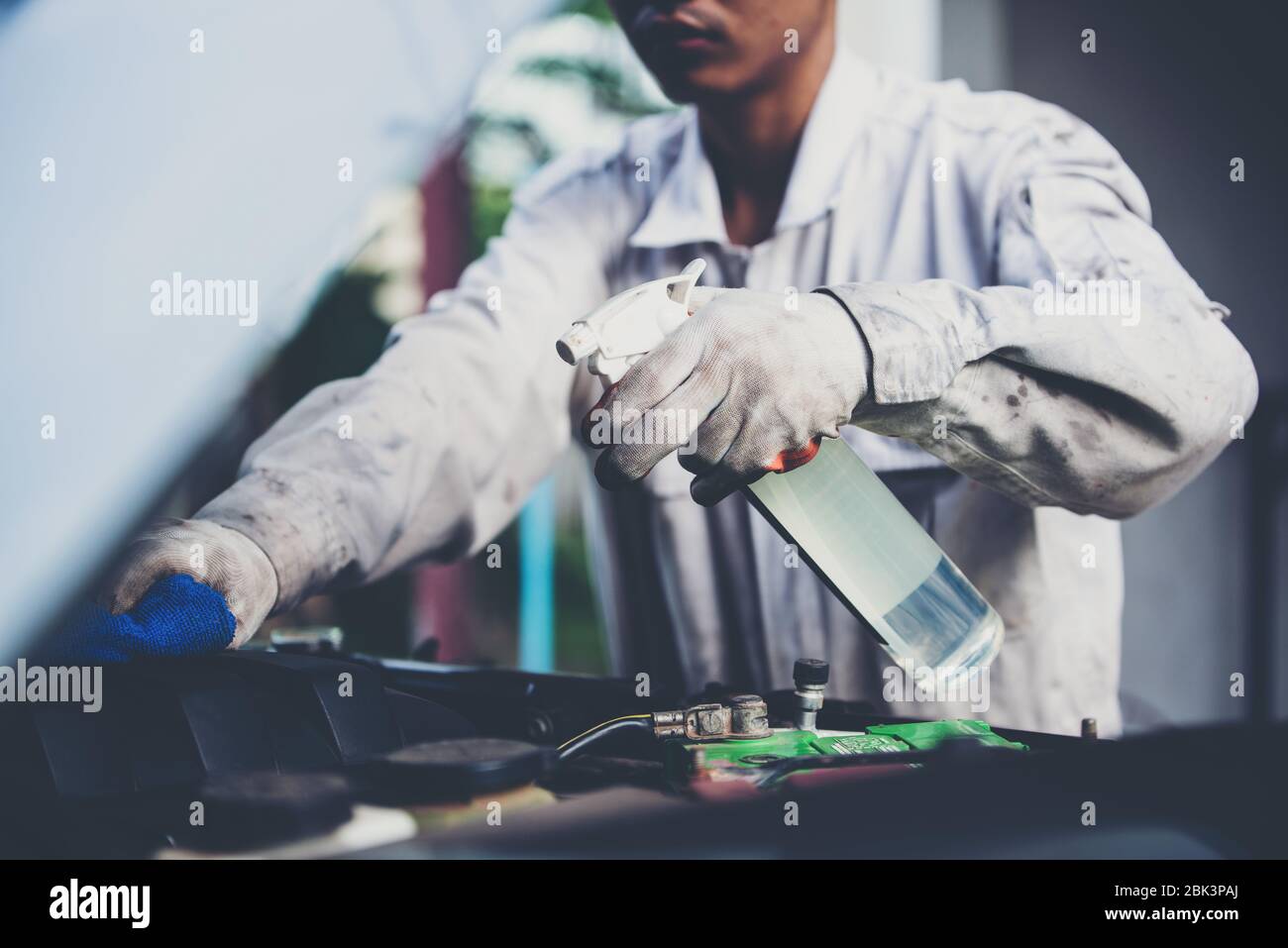 Car wash worker wearing a white uniform standing a sponge to clean the
