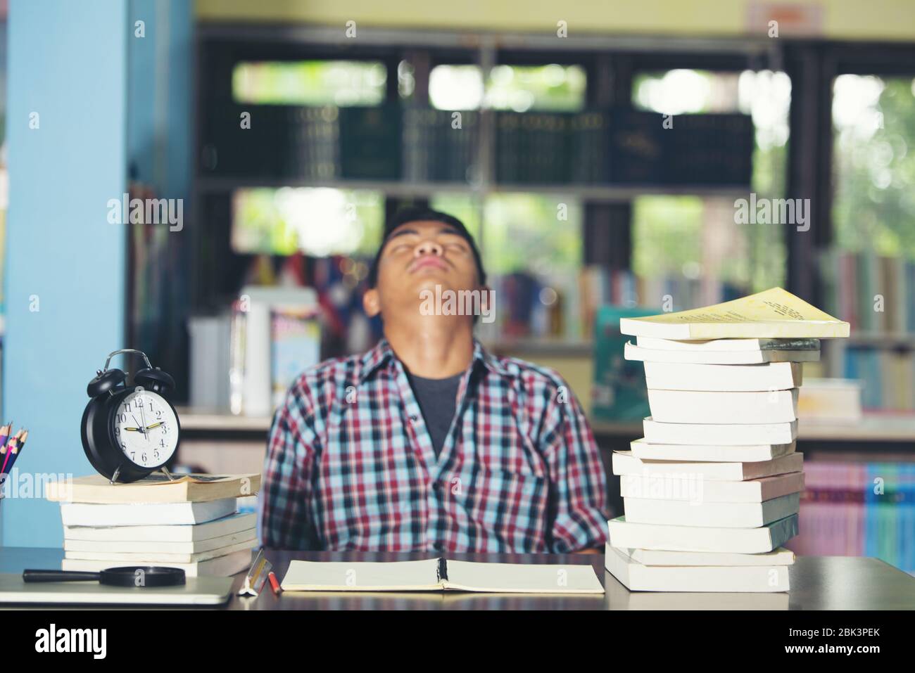 Educational conept: tired student in a library Stock Photo - Alamy