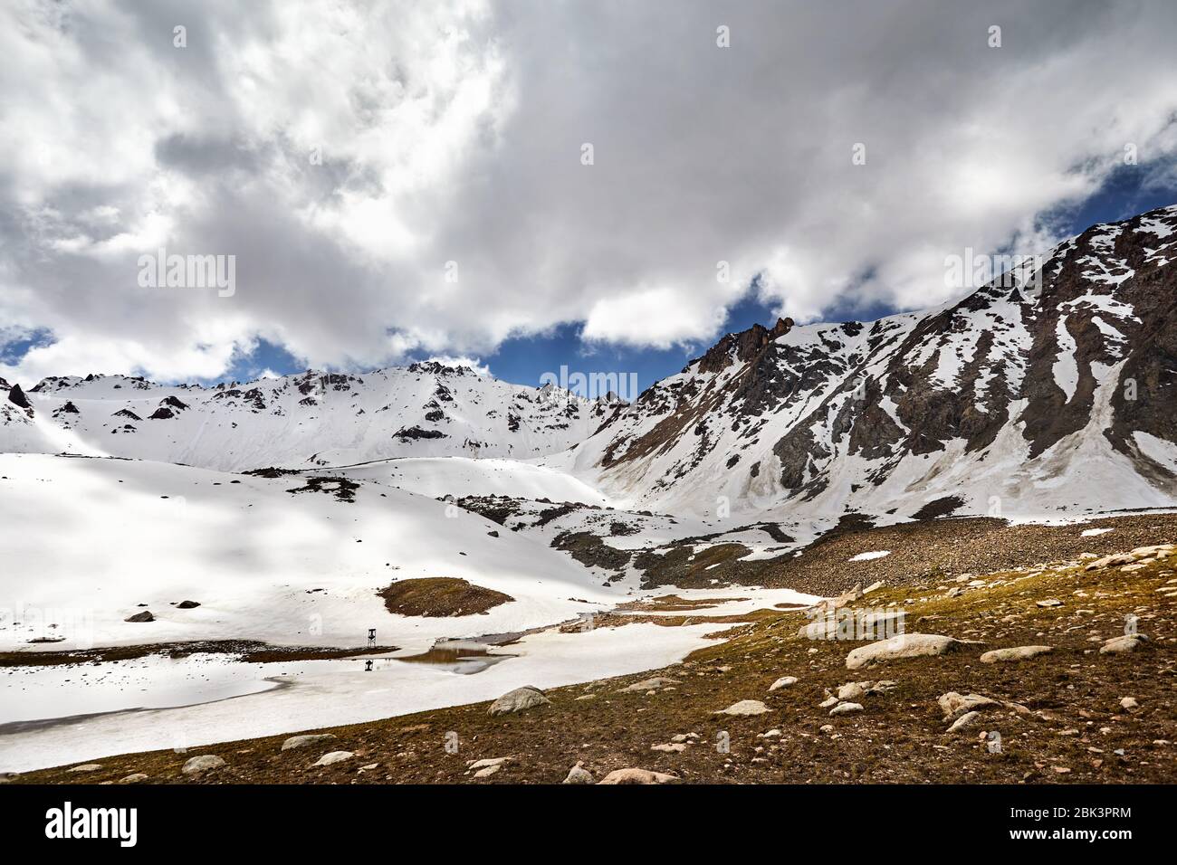 Landscape of snow mountain valley and lake against cloudy sky in Kazakhstan Stock Photo