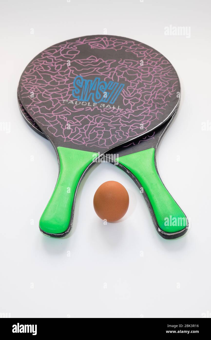 Two beach tennis rackets are resting on a white background, in the centre there is an egg that replaces the ball, concept of sports nutrition. Stock Photo