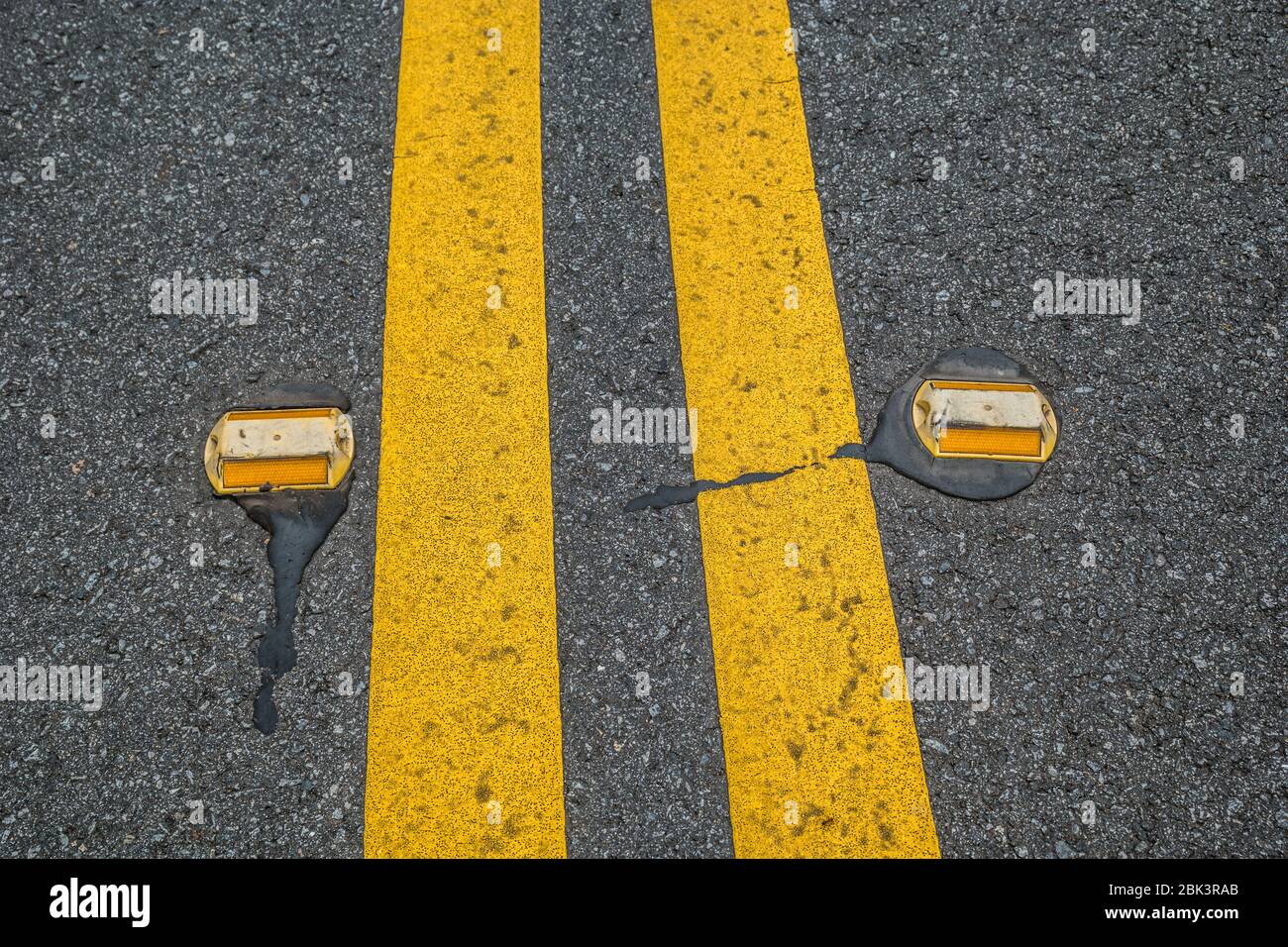 A double yellow line on the street with lane reflectors on both sides
