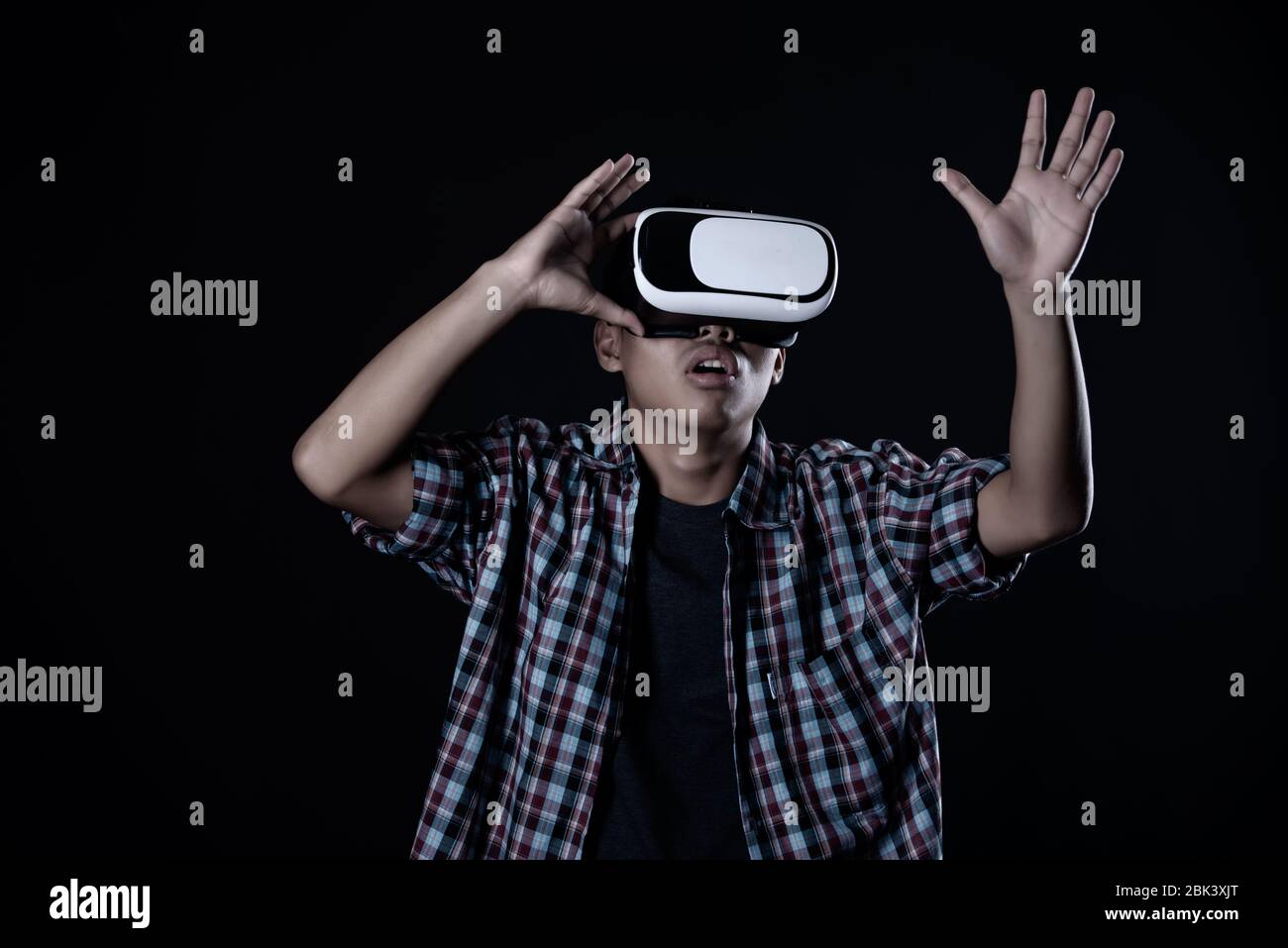 Student man wearing virtual reality goggles in studio,Smartphone using with VR headset. Stock Photo