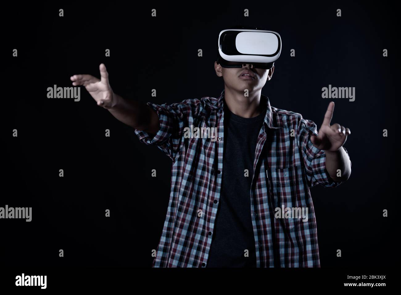 Student man wearing virtual reality goggles in studio,Smartphone using with VR headset. Stock Photo