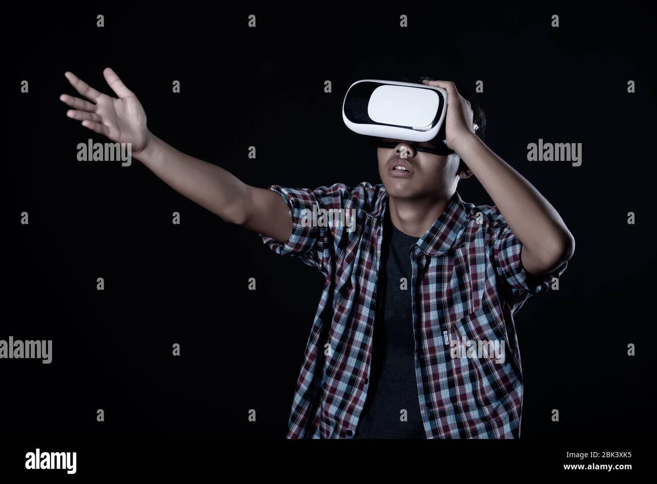 Student man wearing virtual reality goggles in studio,Smartphone using with VR headset. Stock Photo