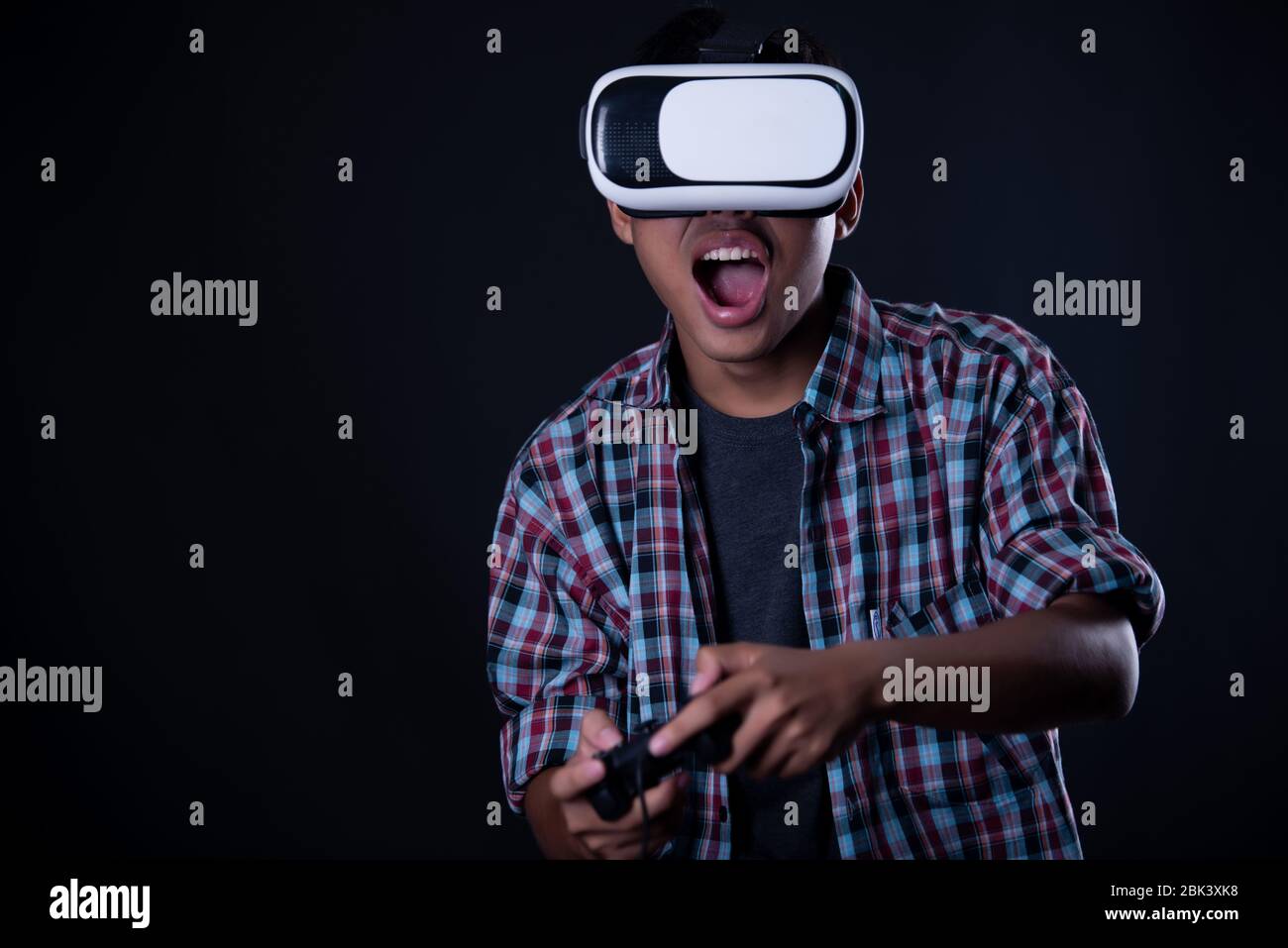 Student man wearing virtual reality goggles in studio,Smartphone using with VR headset. Stock Photo