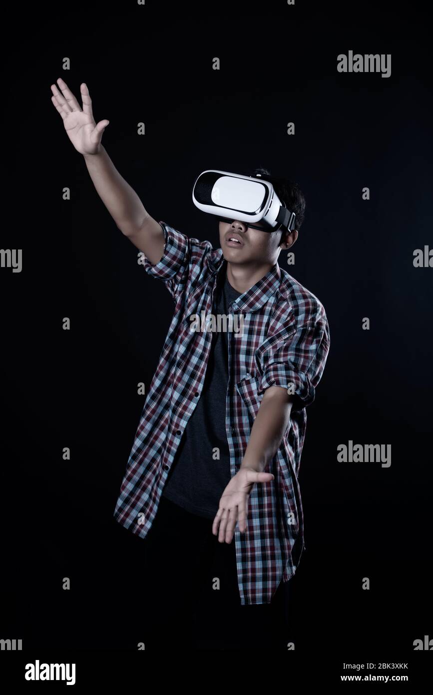 Student man wearing virtual reality goggles in studio,Smartphone using with VR headset. Stock Photo