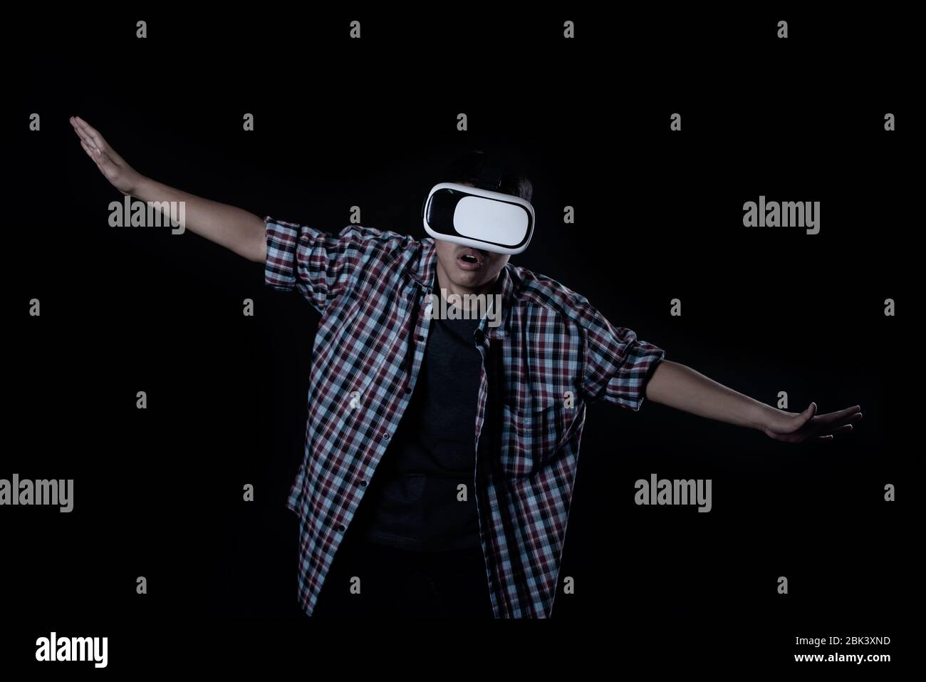 Student man wearing virtual reality goggles in studio,Smartphone using with VR headset. Stock Photo
