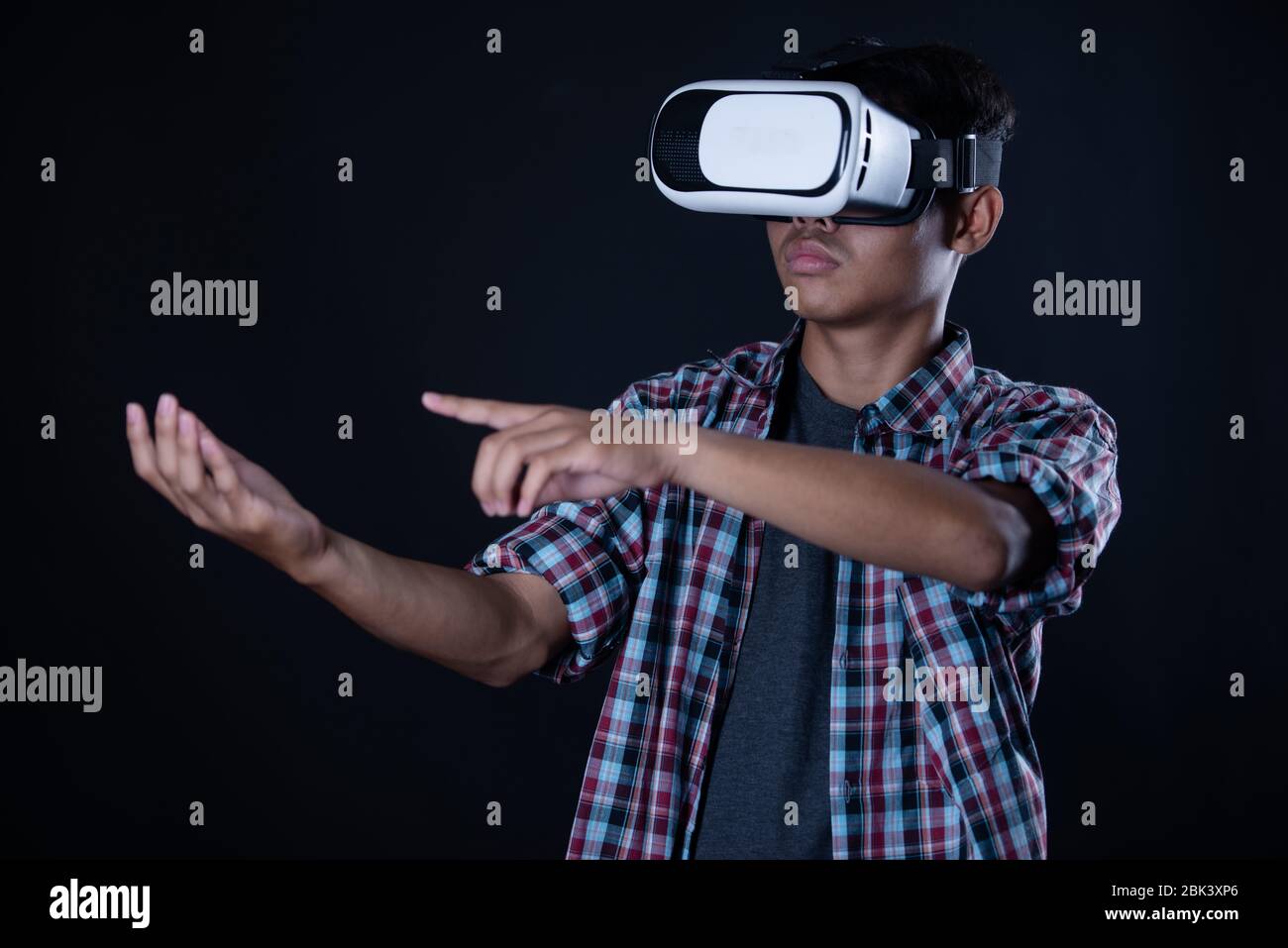 Student man wearing virtual reality goggles in studio,Smartphone using with VR headset. Stock Photo