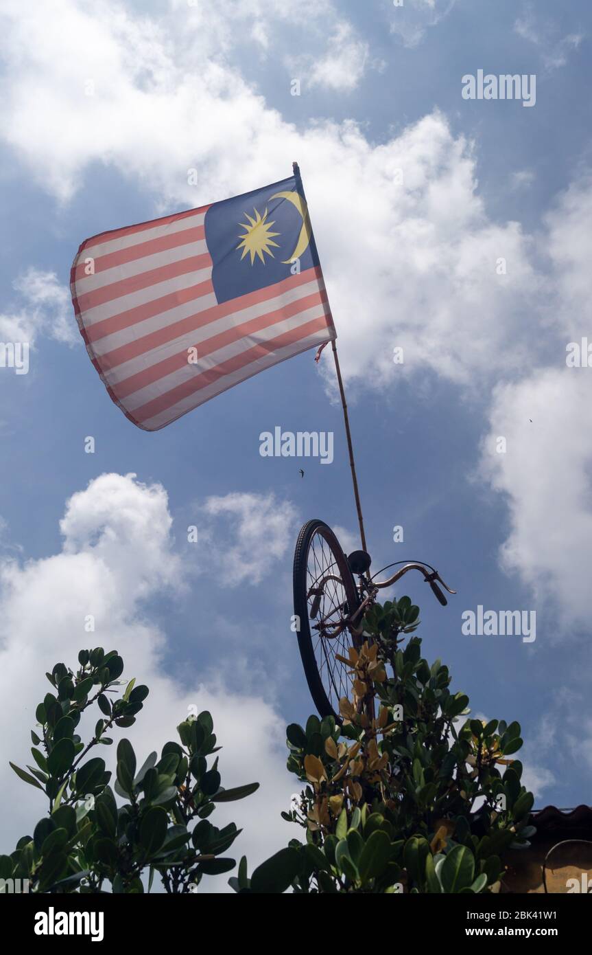 Malaysia flag hang on bicycle under blue sky white cloud afternoon. Stock Photo