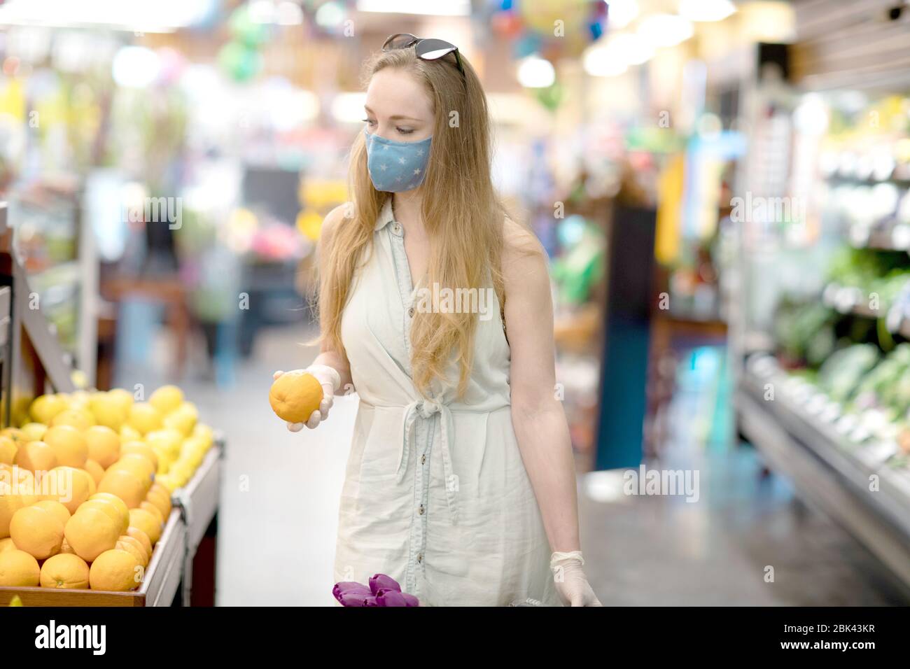 A young woman in a grocery store wearing a face mask and disposable ...