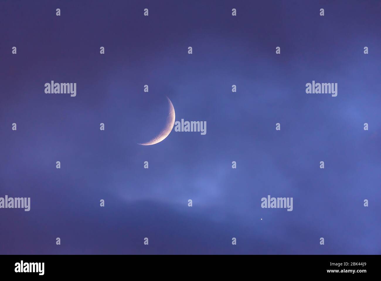 Crescent moon over the cloudy sky at sunset by the planet Venus. Background design Stock Photo