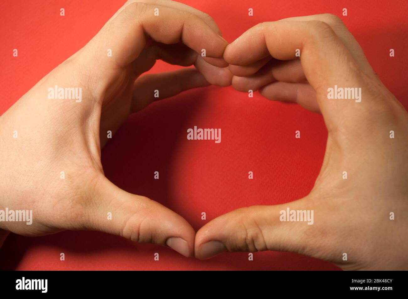 heart of man hands 18 years old on red background, love Stock Photo