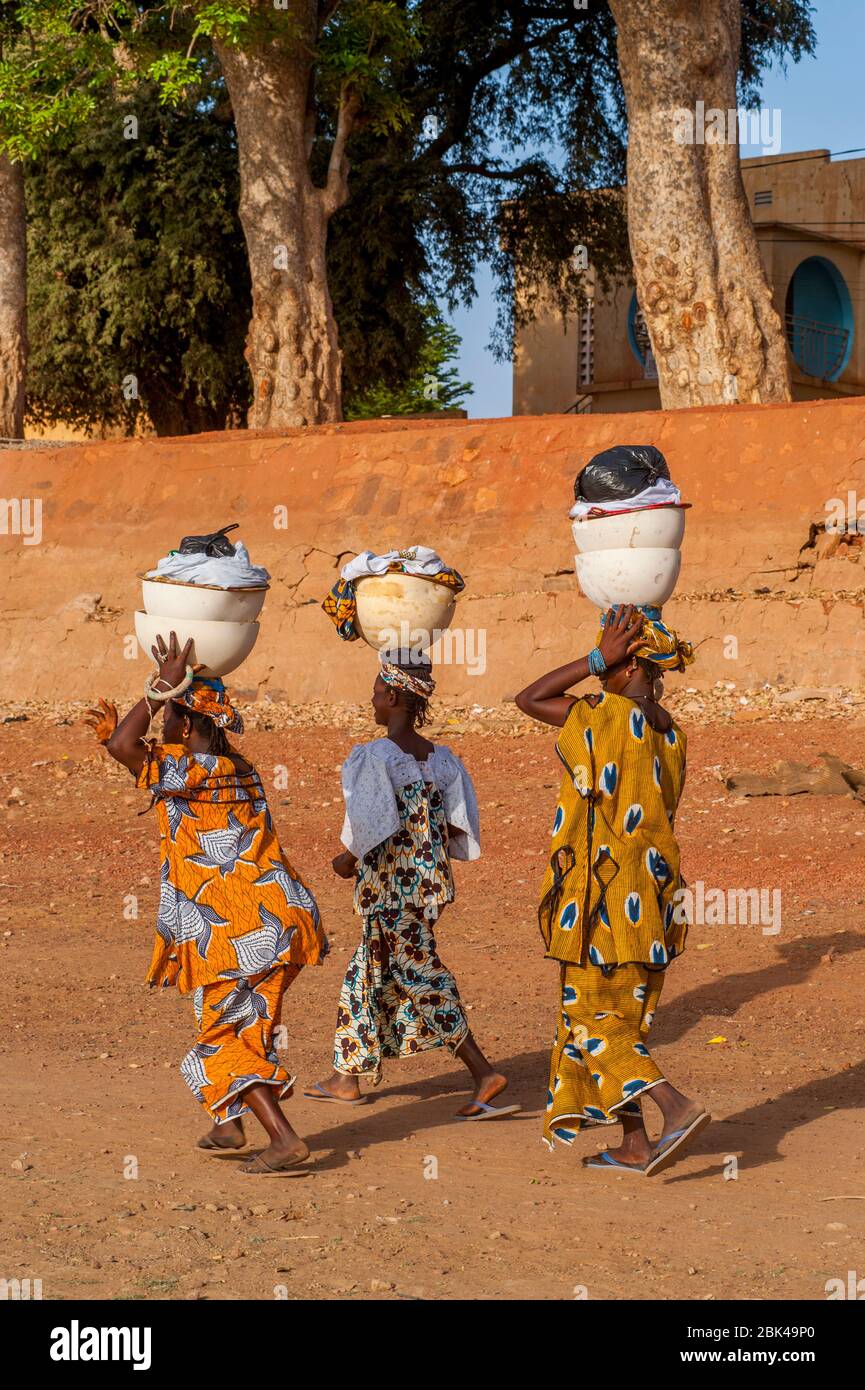 Local women walking and carrying the laundry on their head on the shore of the Bani River in Mopti in Mali, West Africa. Stock Photo