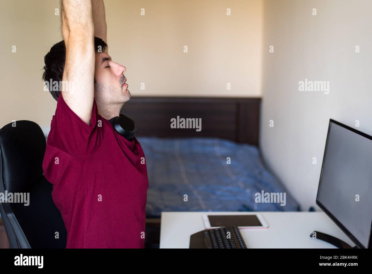 Man stretching while working from home in an improvised office in the living room Stock Photo