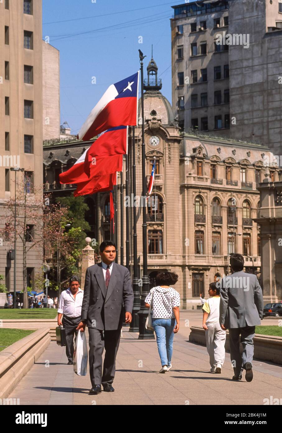 SANTIAGO, CHILE - People walk under Chilean flags at Constitution Plaza near La Moneda. Stock Photo