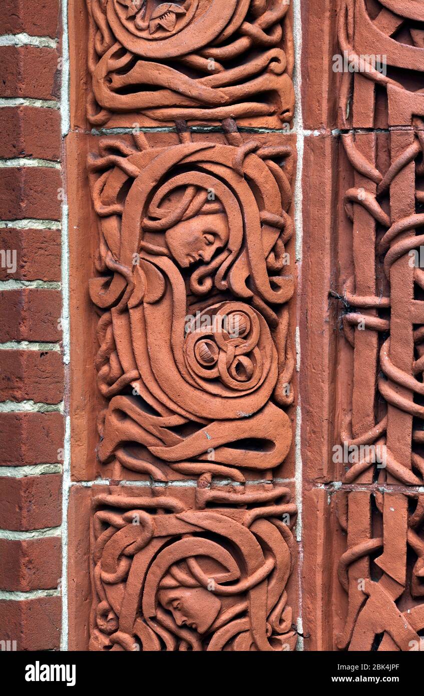 Close up of a terracotta image of a kneeling figure by the entrance door to the Watts Memorial Chapel, Compton, Surrey. Stock Photo