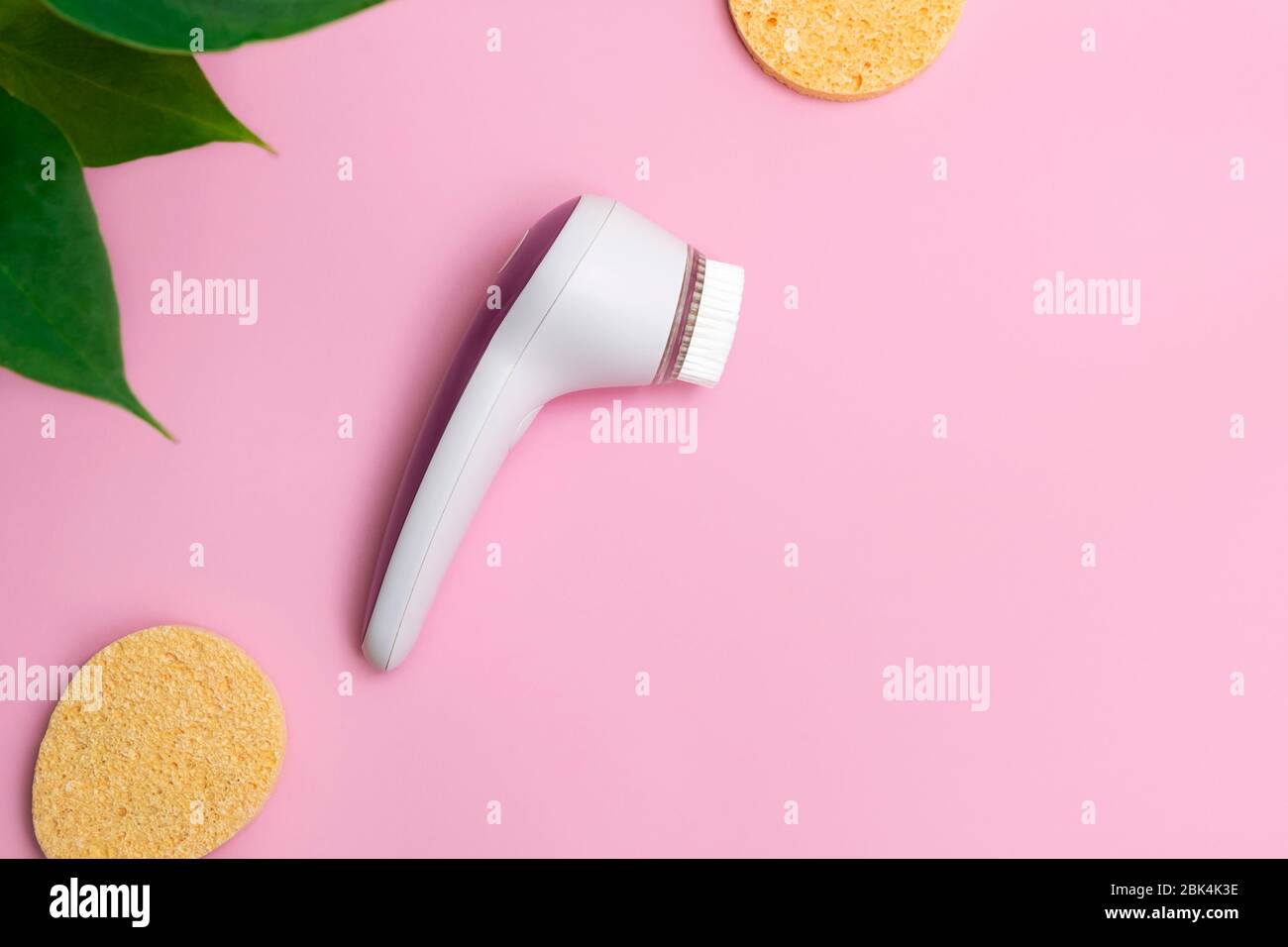 Facial cleansing brush with face sponges on soft pink background. Top view with copy space Stock Photo