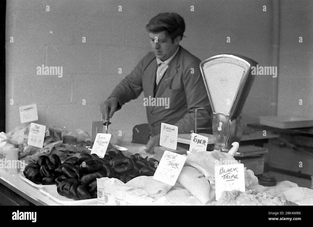 A male stallholder selling tripe and black puddings and other food on Longsight Market, Dickenson Road, Manchester, England, uk, in 1974. Stock Photo