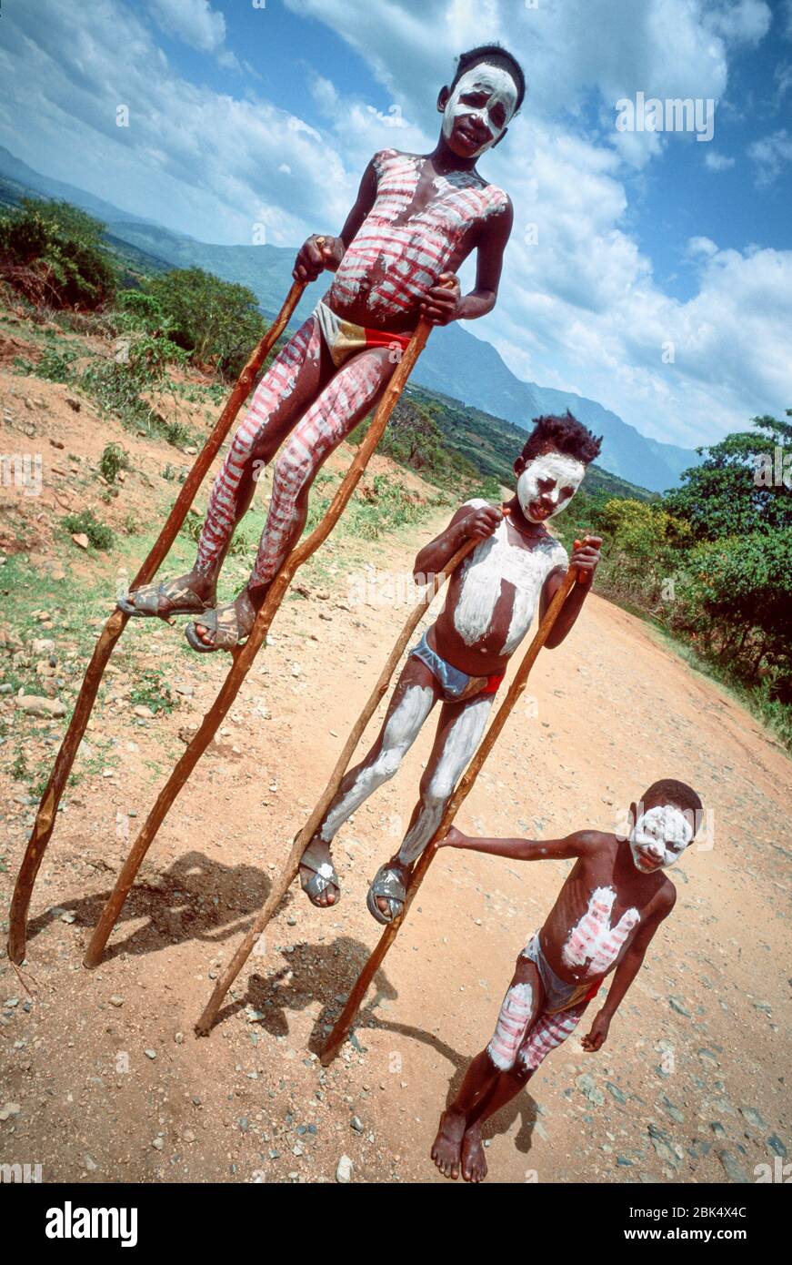 Three Banna tribe boys try to collect some money from passing tourists in their cars by walking on stilts on the dirt road to Jinka. Stock Photo