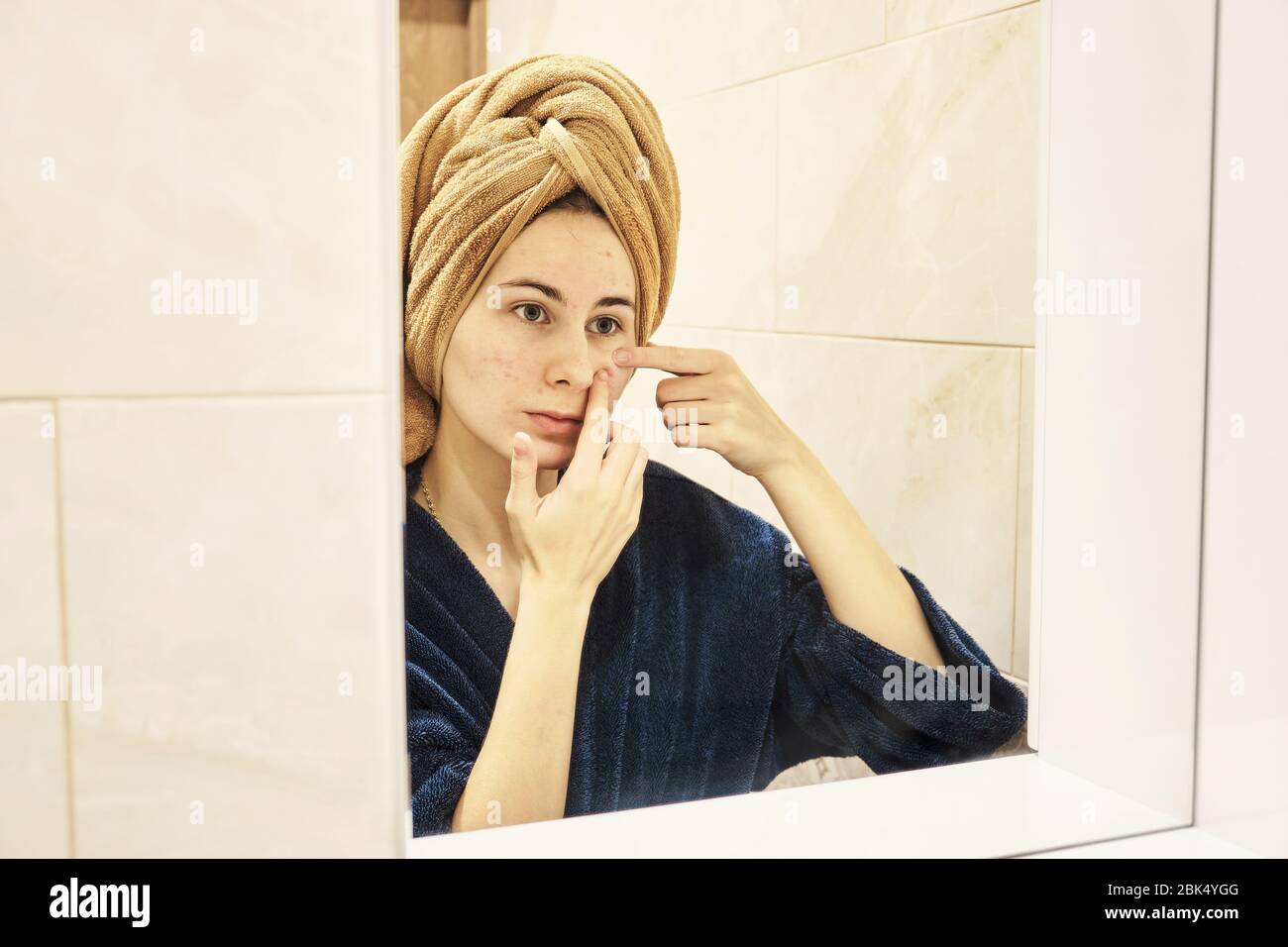 young millennial performs cosmetic procedures in front of a mirror Stock Photo