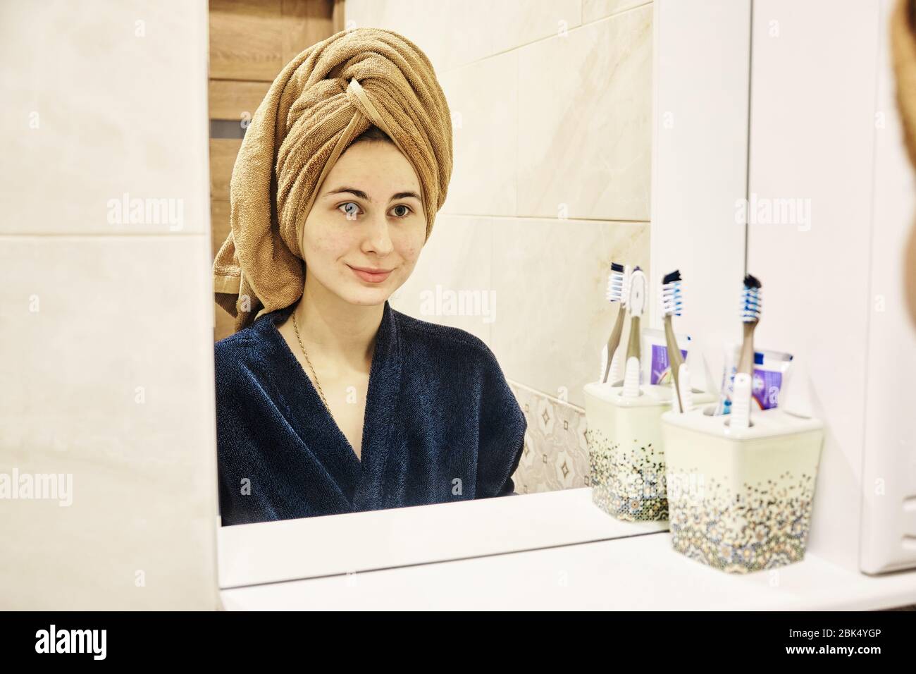 young millennial performs cosmetic procedures in front of a mirror Stock Photo