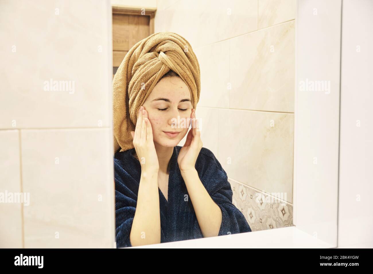 young millennial performs cosmetic procedures in front of a mirror Stock Photo
