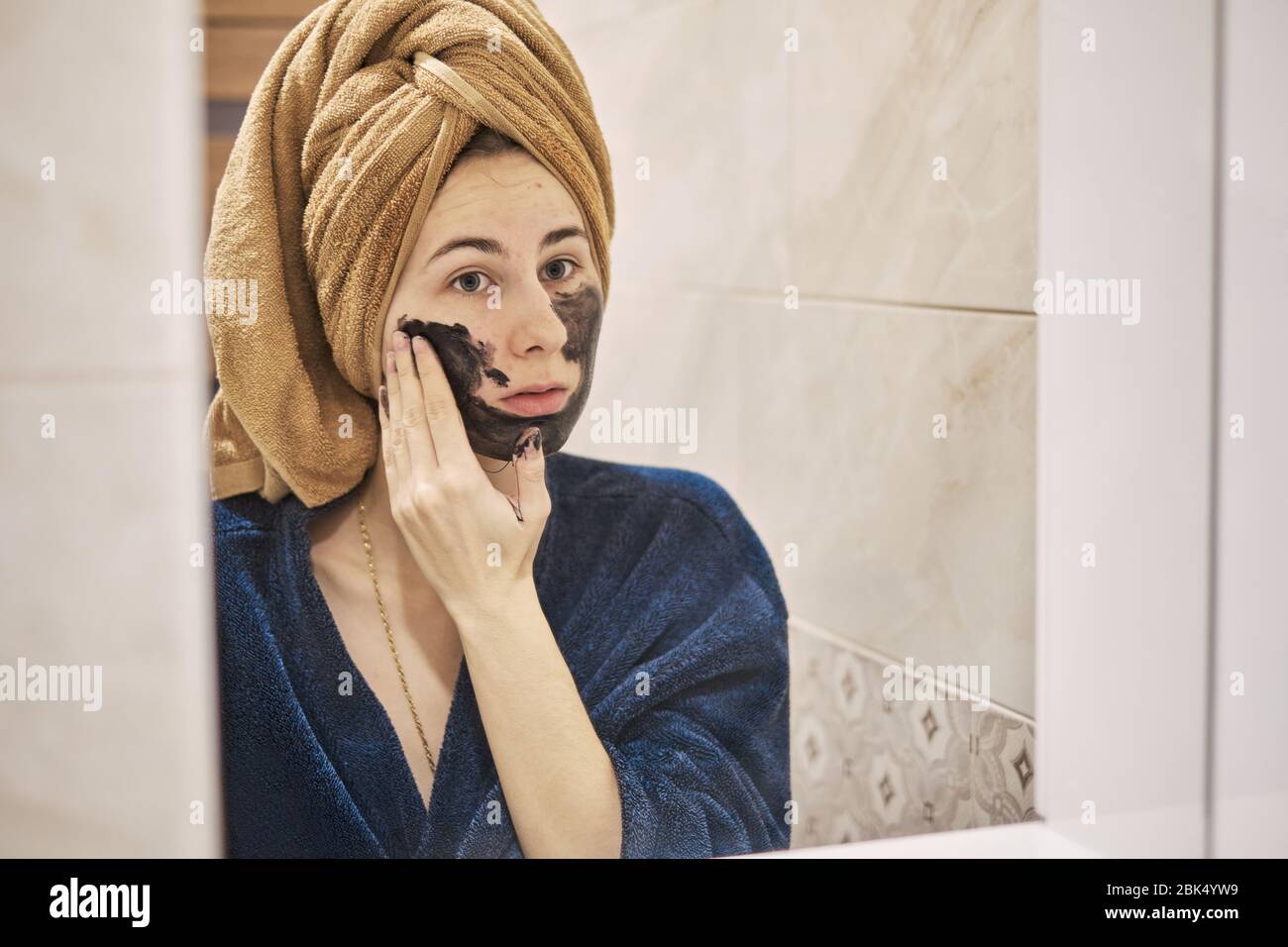 young millennial performs cosmetic procedures in front of a mirror Stock Photo