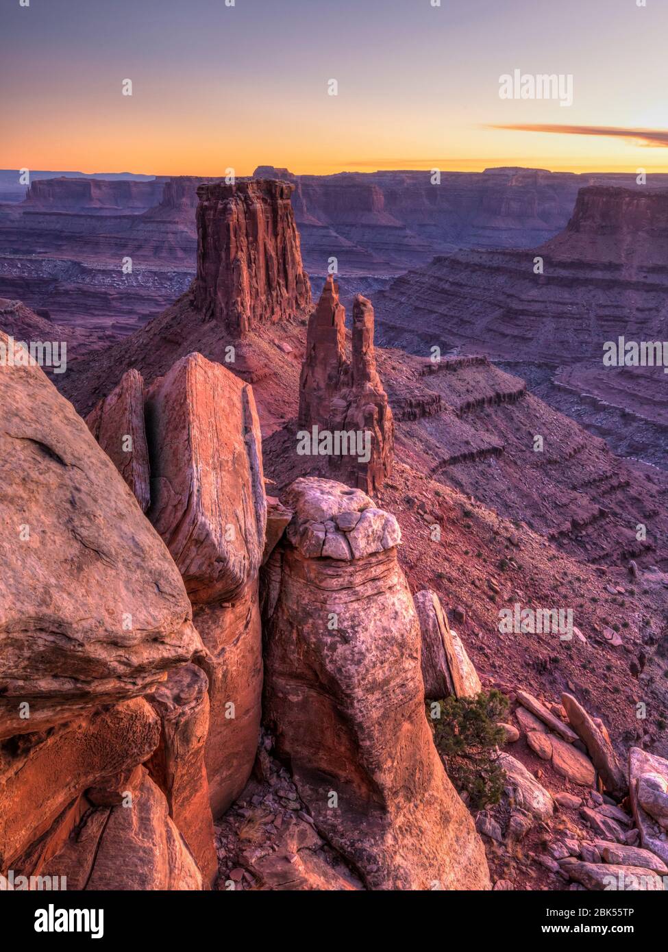 A broken cliff on Marlboro Point fronts the iconic double spire and butte in Shafer Canyon in Canyonlands National Park, Utah. Stock Photo