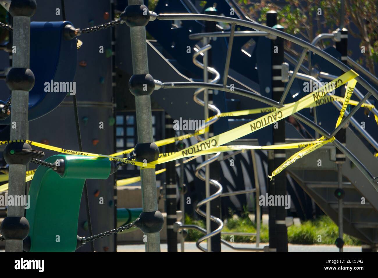 Closed city park and off limits playground covered in yellow caution tape due to Coronavirus COVID19 outbreak. Doyle Hollis Park, Emervyille, CA. Stock Photo