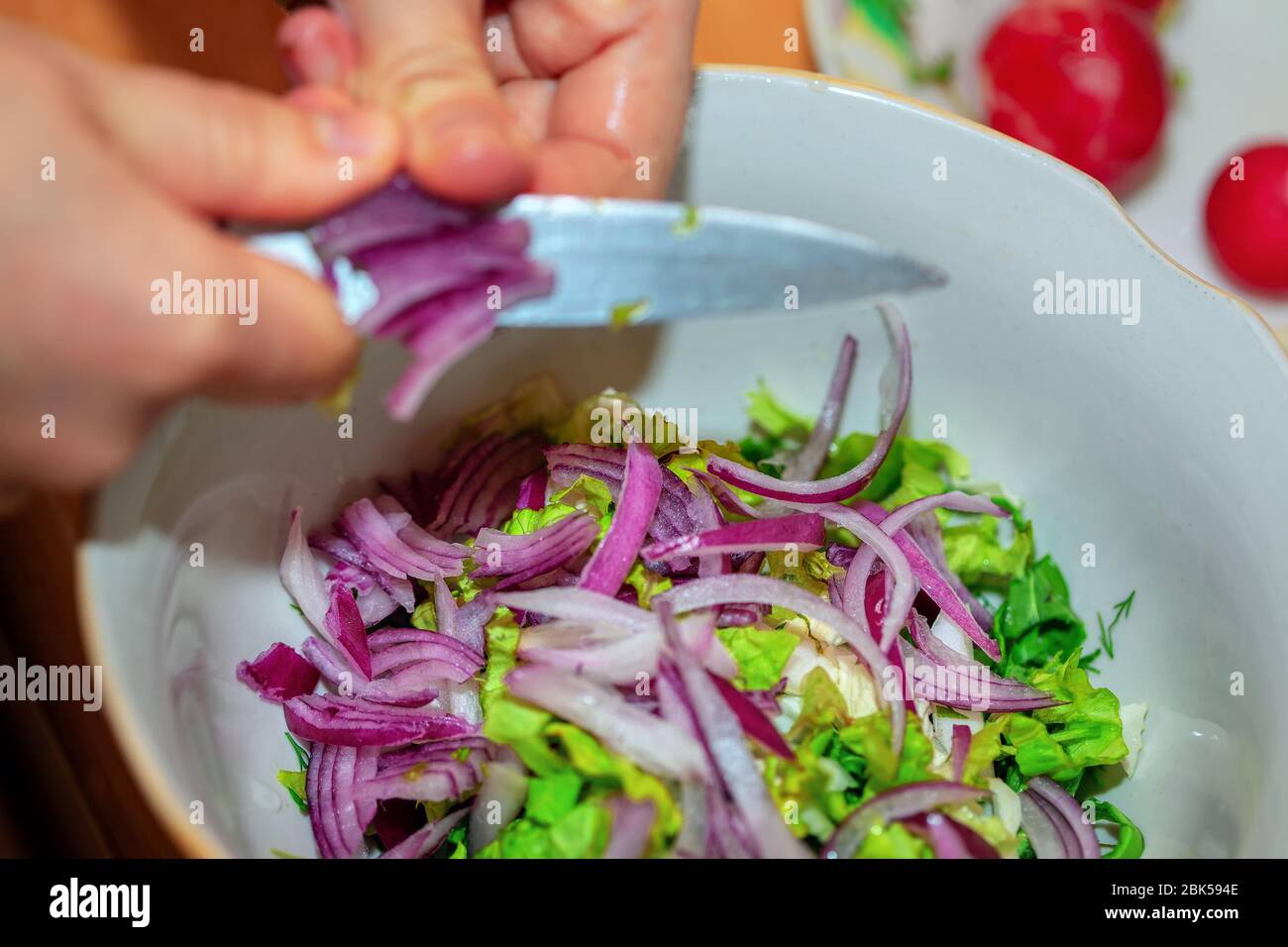 Woman's hands with knife cut onion for salad Stock Photo - Alamy