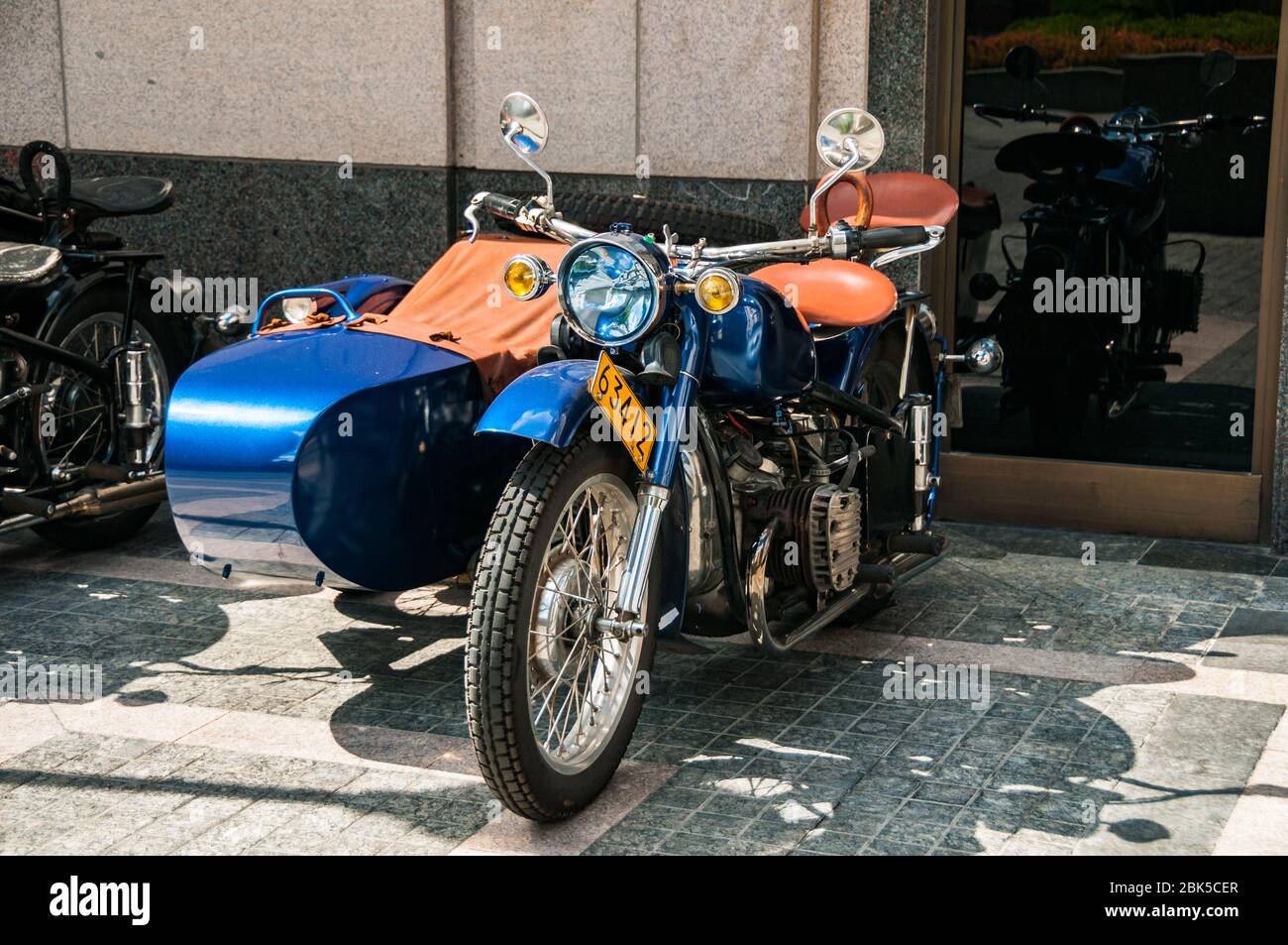 A gleaming blue Changjiang 750 motorcycle sidecar outside the Peninsula Hotel awaiting the start of a Shanghai Insiders tour and reflected in the wind Stock Photo