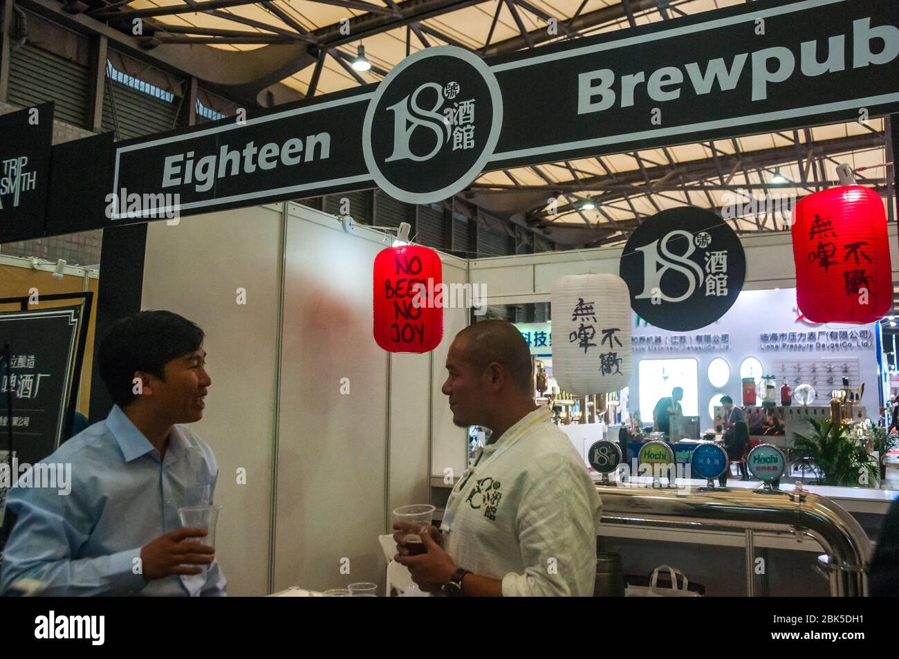 Wuhan's 18 Brewpub's stall at 2016 China Craft Beer Summit in Shanghai. Brewmaster Jiang Qi (right) speaks to customer. Stock Photo